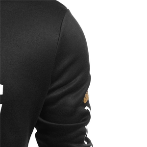 Detailed view of black hoodie sleeve with gold crown and white letter printing