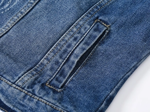 Détail d'une veste en jean bleue montrant les coutures jaunes et la texture délavée