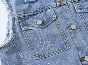 Vue détaillée du gilet en jean bleu clair avec strass en cristal et bords effilochés