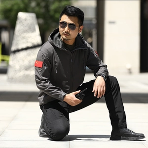 Detail of grey tactical softshell jacket sleeve with flag patch and zipper pocket