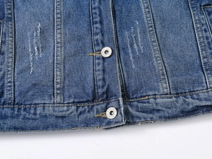 Détails de la veste en jean bleue montrant les boutons métalliques et les coutures