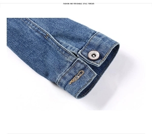 Détail du poignet d'une veste en jean bleue avec coutures contrastées et bouton métal