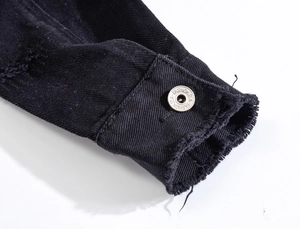 Detail of frayed cuffs on black denim jacket with engraved silver button design