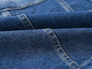 Détail macro du tissu denim bleu foncé avec doubles surpiqûres jaunes de haute qualité