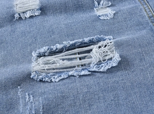 Vue macro détaillée des trous déchirés sur la texture du tissu denim bleu clair