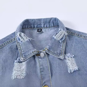 Détail d'un gilet en jean bleu clair délavé avec col déchiré et boutons en métal argenté