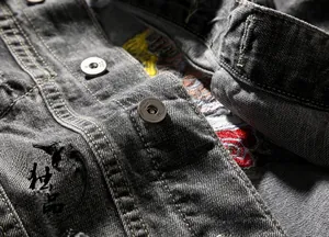 Detail of grey denim vest showing rose embroidery and silver metallic buttons