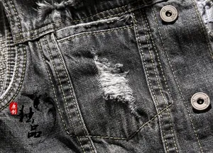 Macro view of distressed grey denim vest featuring vintage holes and branded metal buttons