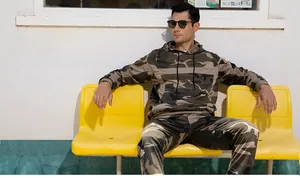 Detail of camouflaged hoodie with drawstring and ribbed cuffs on a male tracksuit