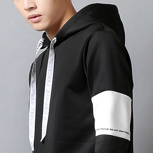 Detail of black hoodie with white drawstrings and decorative text on sleeve and cord