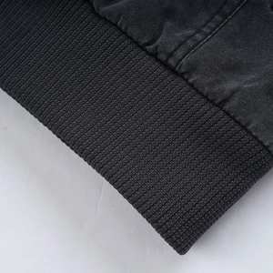Detail of dark grey washed cotton jacket showing ribbed knit cuff and stitching texture