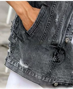 Close-up of distressed grey denim vest featuring metal rivets and embroidery detail