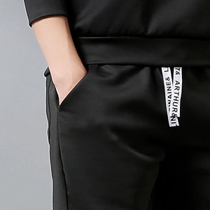 Detail of men's black joggers featuring elastic waist and letter printed drawstrings