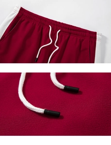 Detail of dark red sports shorts featuring elastic waistband and white contrast side stripes