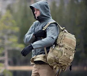 Giacca tattica softshell abbinata a zaino kaki con sistema MOLLE per attività all'aperto
