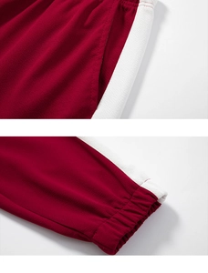 Detail of red sports pants featuring white side stripes and elastic ribbed cuffs for men
