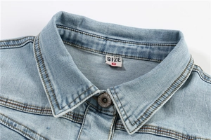 Detail of light wash denim collar with brass button and S-size label on the neck