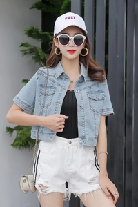 Detail of light blue denim short sleeve jacket with symmetrical flap pockets and wash texture