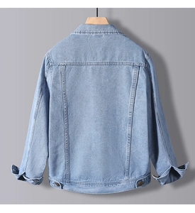 Detail of light blue denim jacket back featuring wash texture and adjustable hem straps
