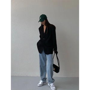 Detail showing oversized black blazer with padded shoulders and chic single shoulder bag