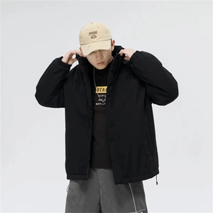Detail of a black windproof jacket paired with a graphic T-shirt and khaki baseball cap