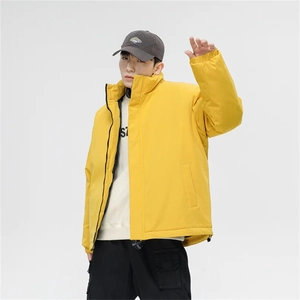 Detail view of yellow stand collar puffer jacket styled with cargo pants and a baseball cap