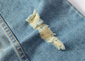 Nahaufnahme der hellblauen Denim-Weste mit Distressed-Effekt und orangefarbenen Nähten