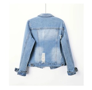 Macro view of light blue denim jacket back featuring distressed ripped details and washed fabric