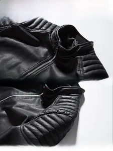 Detail of stand collar and 3D quilted shoulder on a black faux leather biker jacket