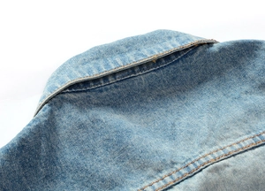 Nahaufnahme der hellblauen Denim-Weste mit detaillierten gelben Nähten an der Schulterpartie