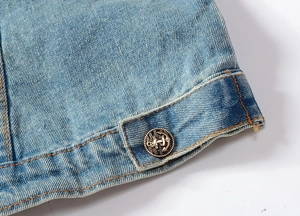 Nahaufnahme von hellblauem Denim mit einem antiken bronzenen Anker-Metallknopf