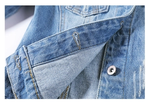 Macro shot of light blue denim jacket fabric texture and durable metal button details