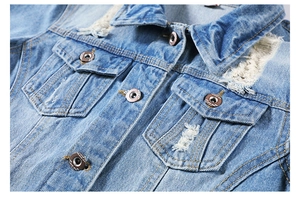 Detailed close-up of light blue denim jacket collar featuring distressed frayed edges and bronze buttons