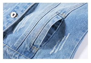 Detailed macro view of denim jacket side pocket with vintage metal button and wash details