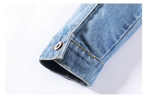 Close-up of light blue denim sleeve with yellow stitching and buttonhole details