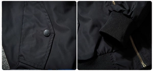 Close-up of black bomber jacket featuring snap pocket, ribbed cuffs and metal zipper