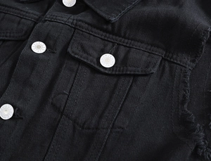 Detail of black denim vest featuring frayed edges and silver jeans embossed buttons