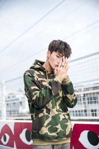 Outdoor street style shot of a camo hoodie with ribbed cuffs and a large kangaroo pocket