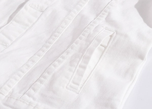Dettaglio delle doppie cuciture e della trama twill su questa giacca in denim bianco
