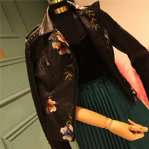 Detailed close-up of floral embroidery and metal studs on black PU leather jacket