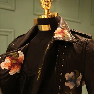 Close-up of floral embroidery and silver stud detailing on black faux leather biker jacket