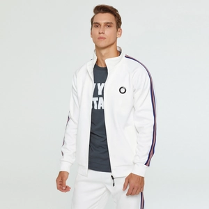 Détail de la veste de sport blanche avec ruban rayé sur les manches et logo circulaire