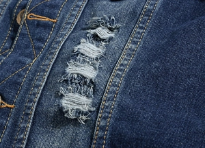 Close-up of dark blue denim vest with ripped distressed details and metal button