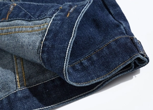 Detailed close-up of dark blue denim stitching and hem texture on slim fit vest