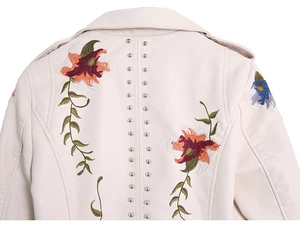Close-up of floral embroidery and silver metal studs on the back of beige PU leather jacket