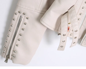 Detail of faux leather jacket with metal studs, zipper sleeve, and floral embroidery