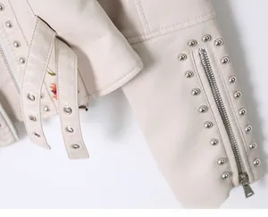 Close-up of beige PU leather jacket featuring silver rivets, zipper cuffs and floral lining