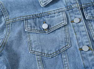 Close-up of vintage blue denim jacket featuring metallic buttons and yellow topstitching