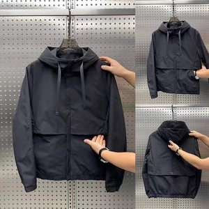 Detail view of black outdoor hooded jacket featuring functional large flap pockets and drawstrings