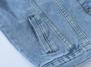 Detailed close-up of light blue denim fabric texture and reinforced side pocket stitching